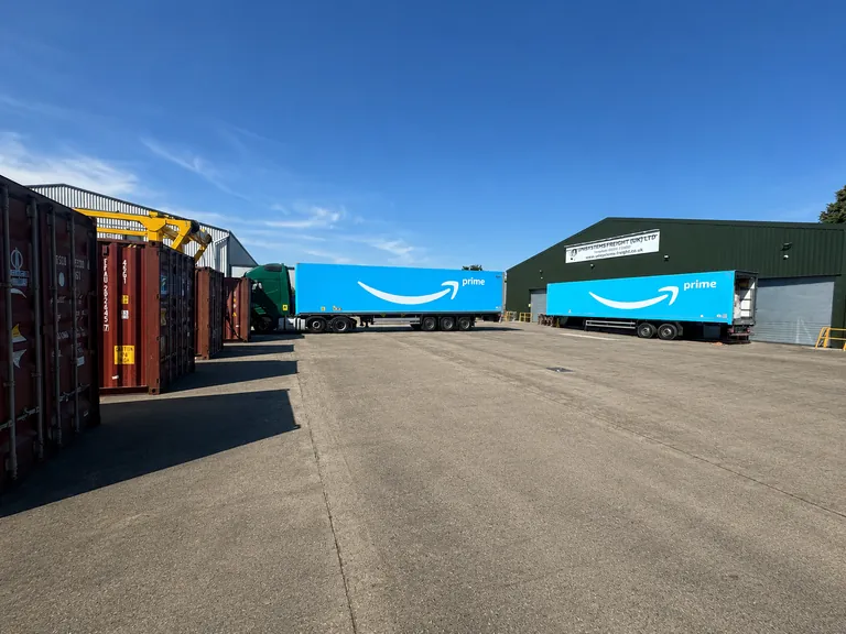 Two Amazon Prime trailers alongside containers in the yard